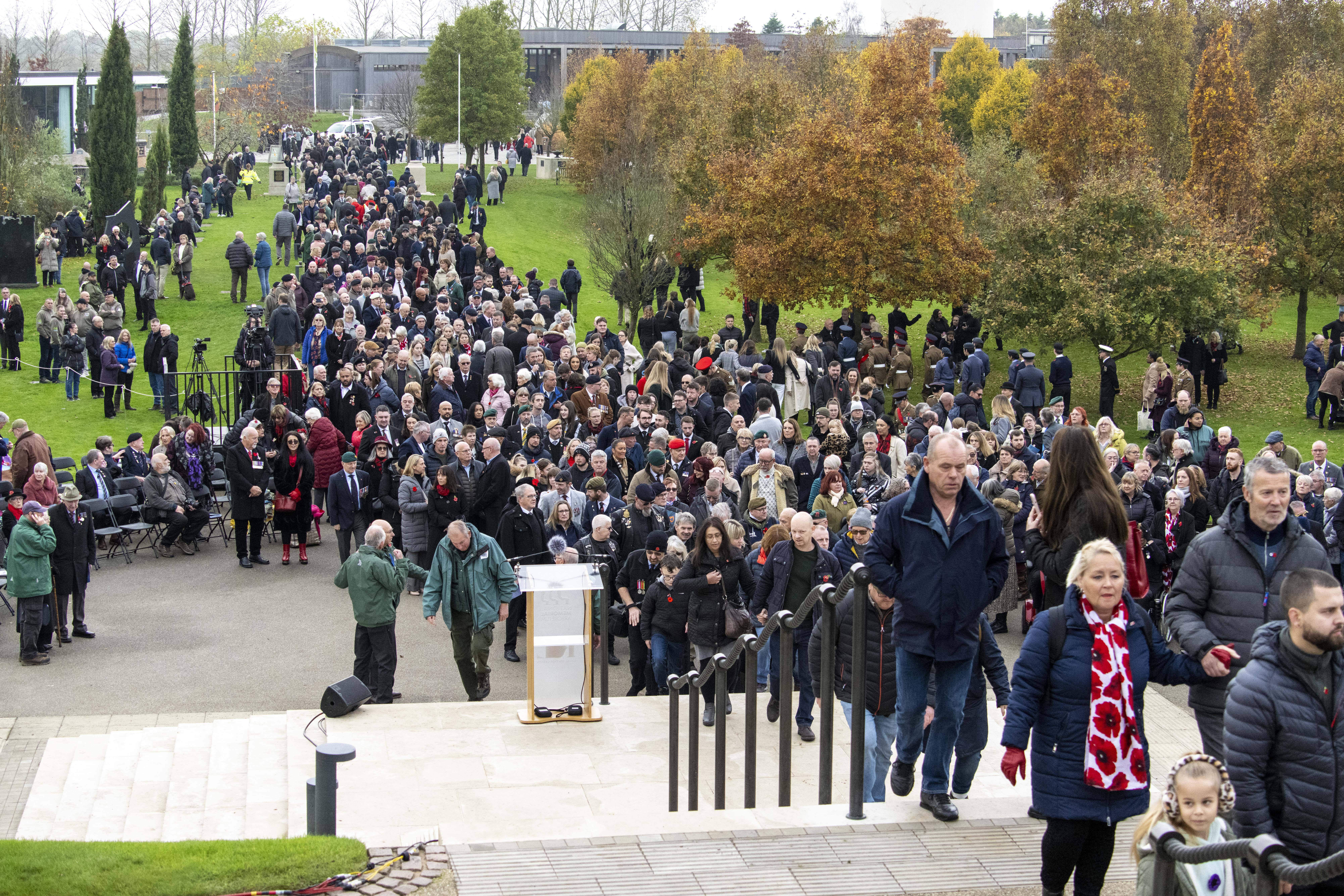 A large crowd of people patinetly wait to asend the steps of the Armed Forces Memorial following the Remembrance Sunday Service.