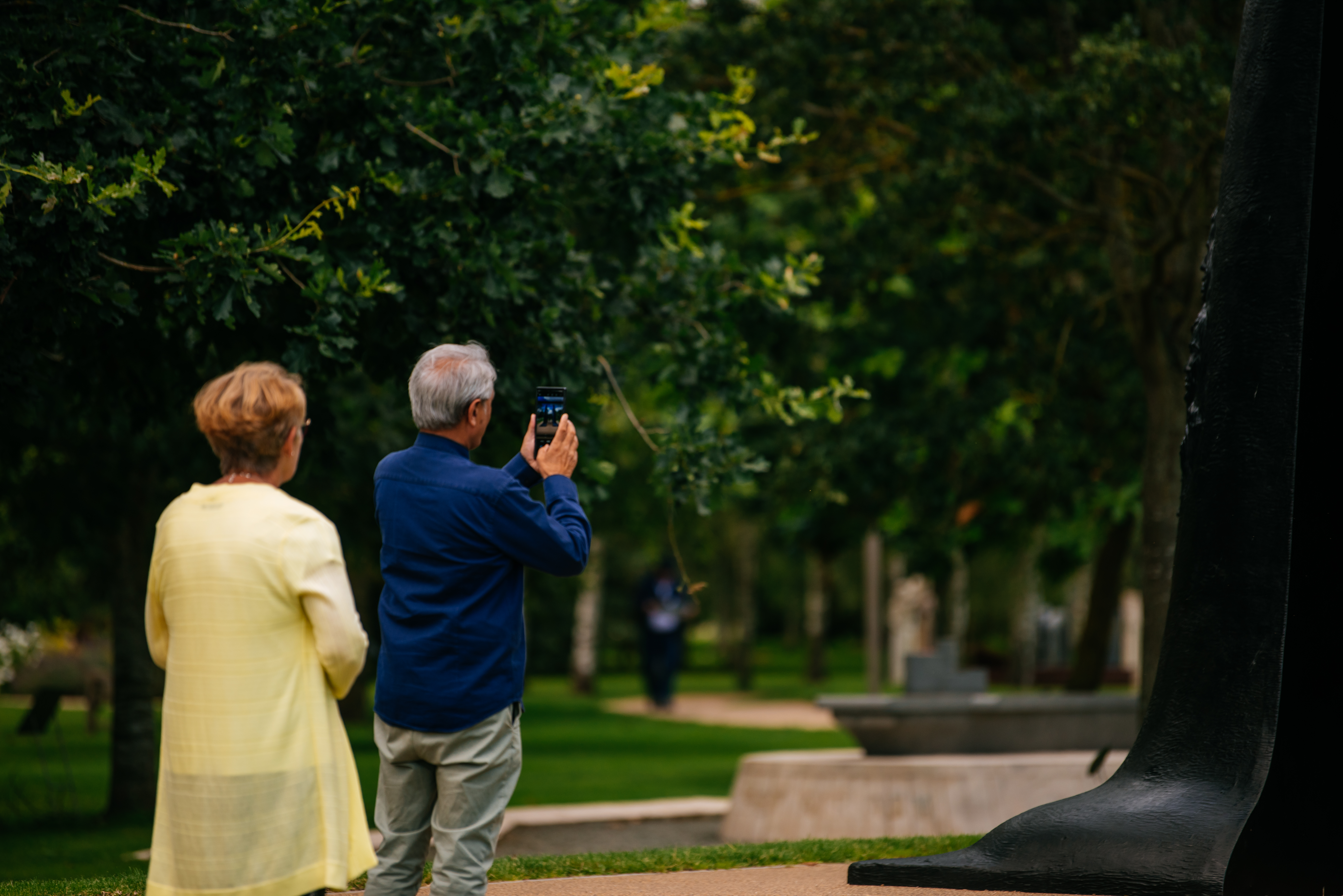 Two visitors looking at a memorial. One is taking a photograph on his phone.