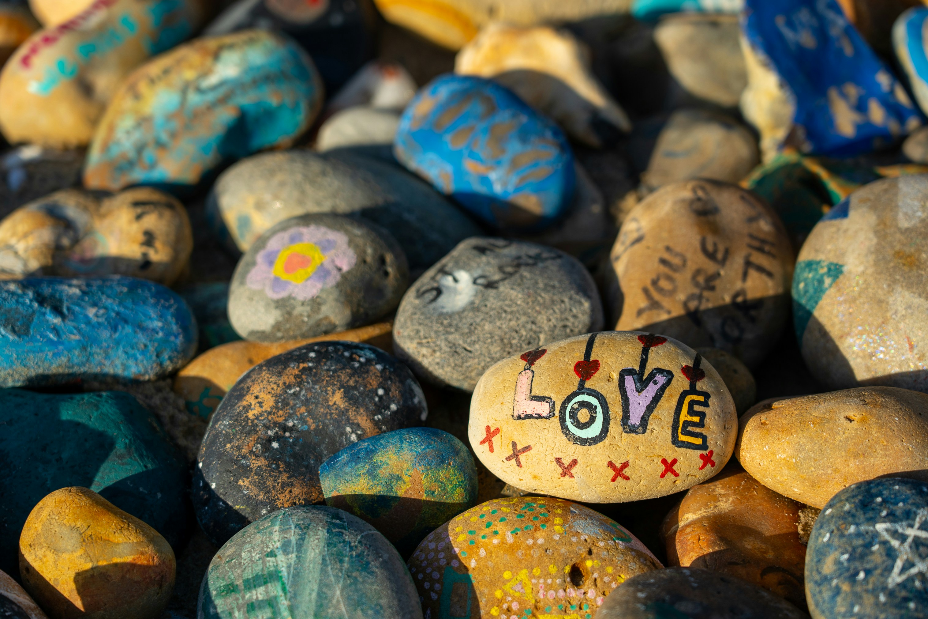 Painted stones sit atop each other forming part of a larger display.