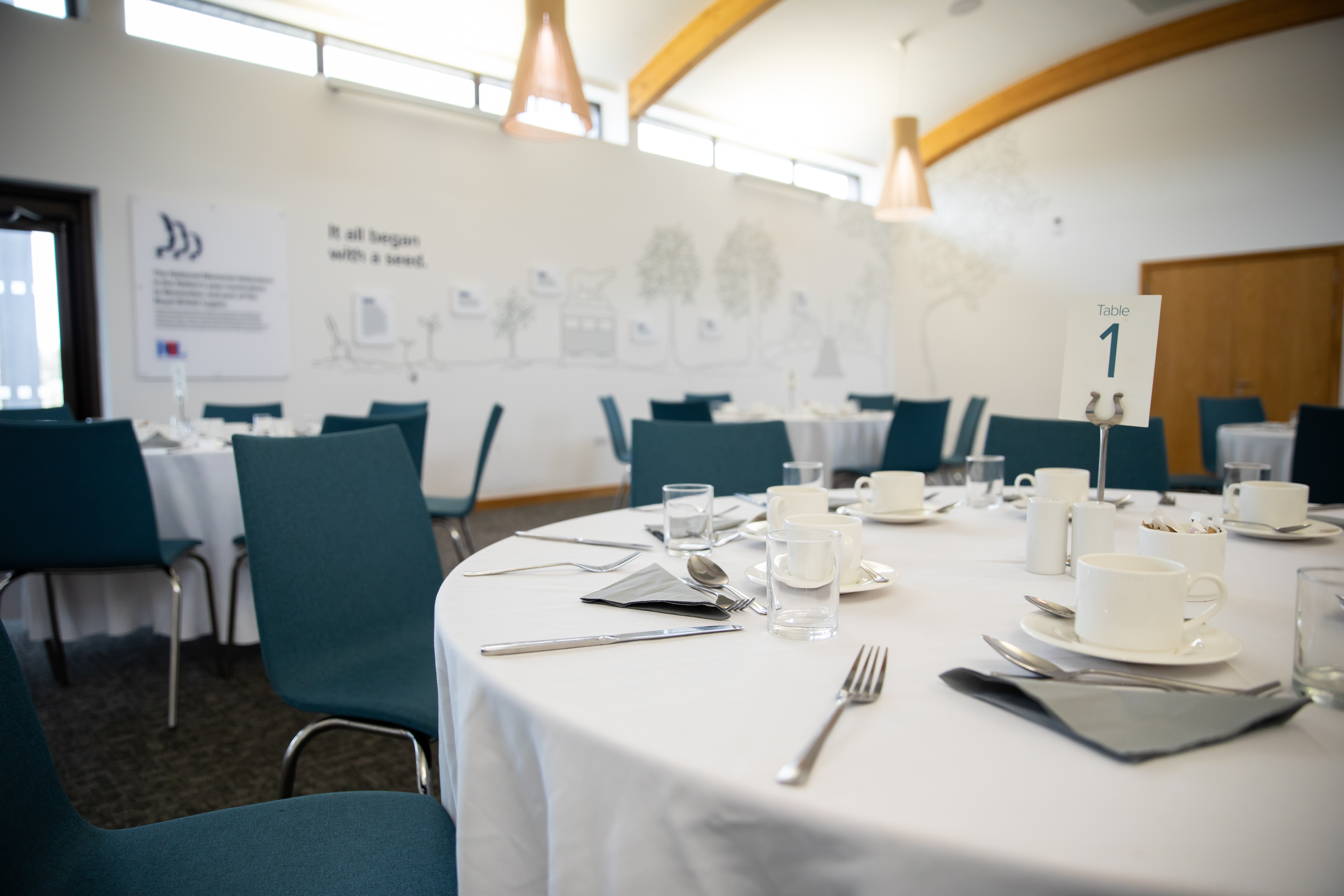 The Founders Room set up with round tables dressed in white table cloths, and laid for dinner.